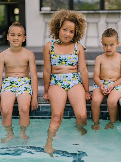 Brothers and sister sitting poolside wearing  Navalora Amalfi Coast Lemon Matching Swimsuits 